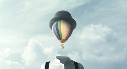 Man_with_hot_air_ballon_as_head_with_blue_sky_and_clouds_behind.jpg