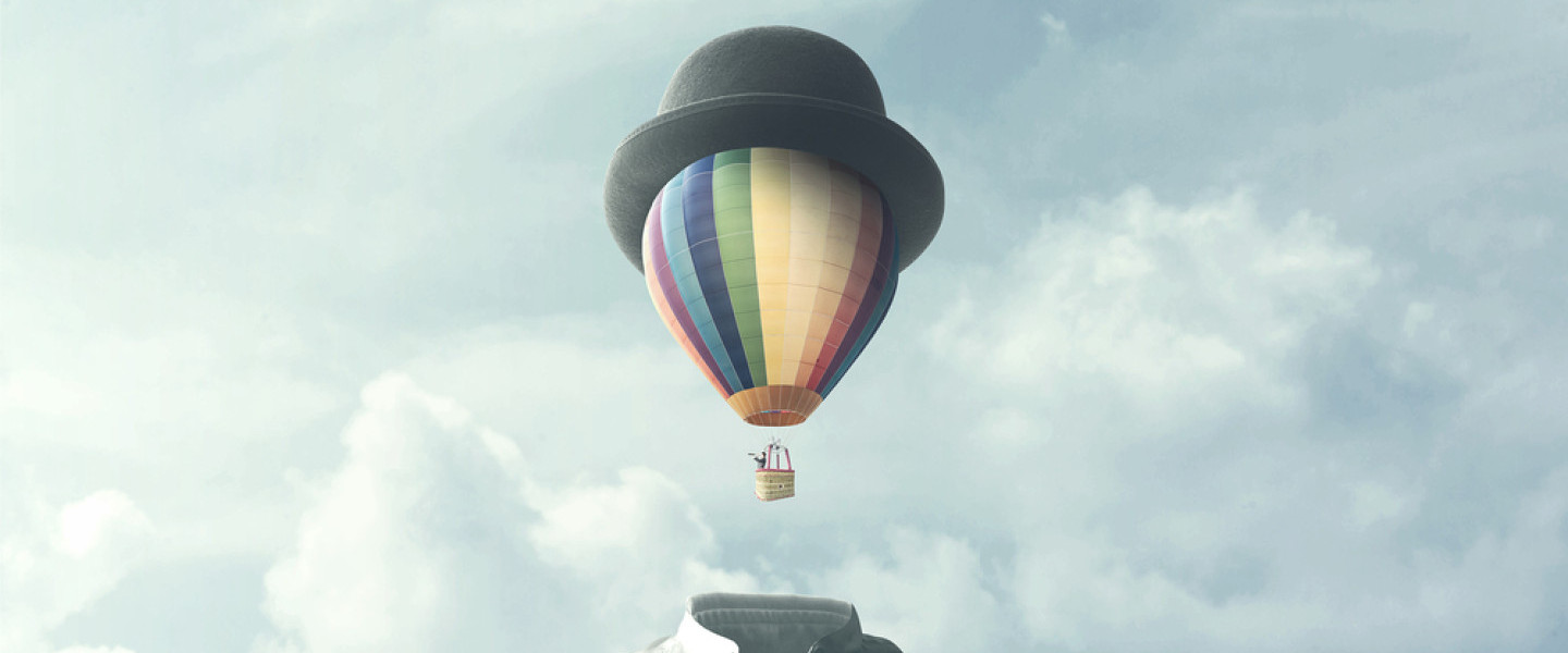 Man_with_hot_air_ballon_as_head_with_blue_sky_and_clouds_behind.jpg