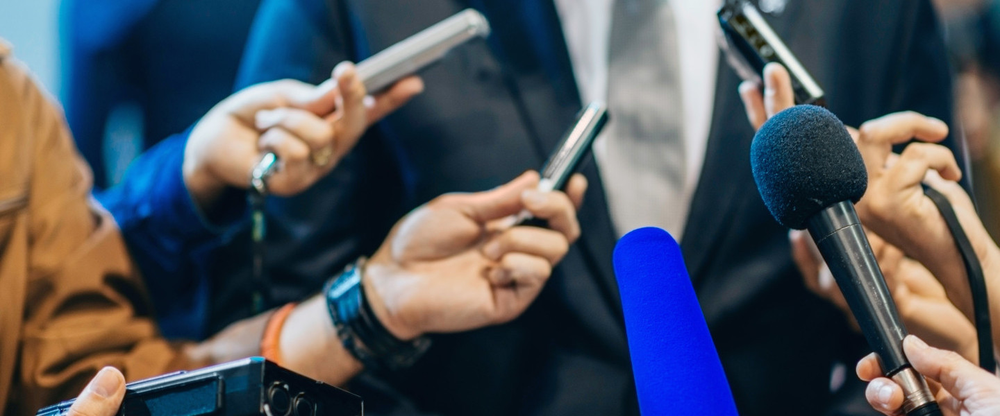 Media_holding_microphones_to_person_in_suit_.jpg