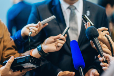 Media_holding_microphones_to_person_in_suit_.jpg