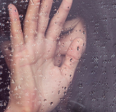 Woman behind rainy glass